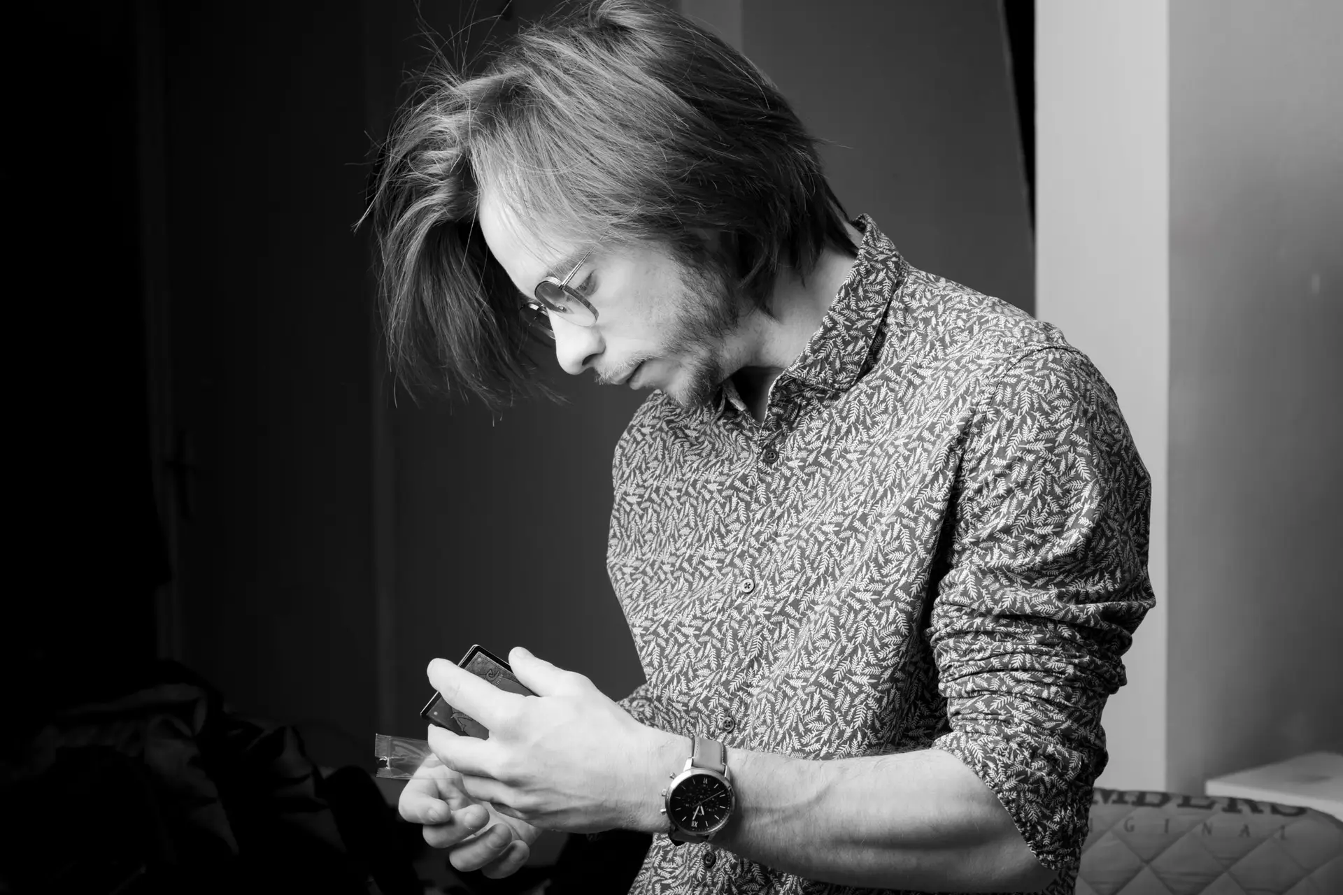 homme au cheveux mi long , le regard fixé sur quelque chose dans sa main , ne regarde pas le professionnel