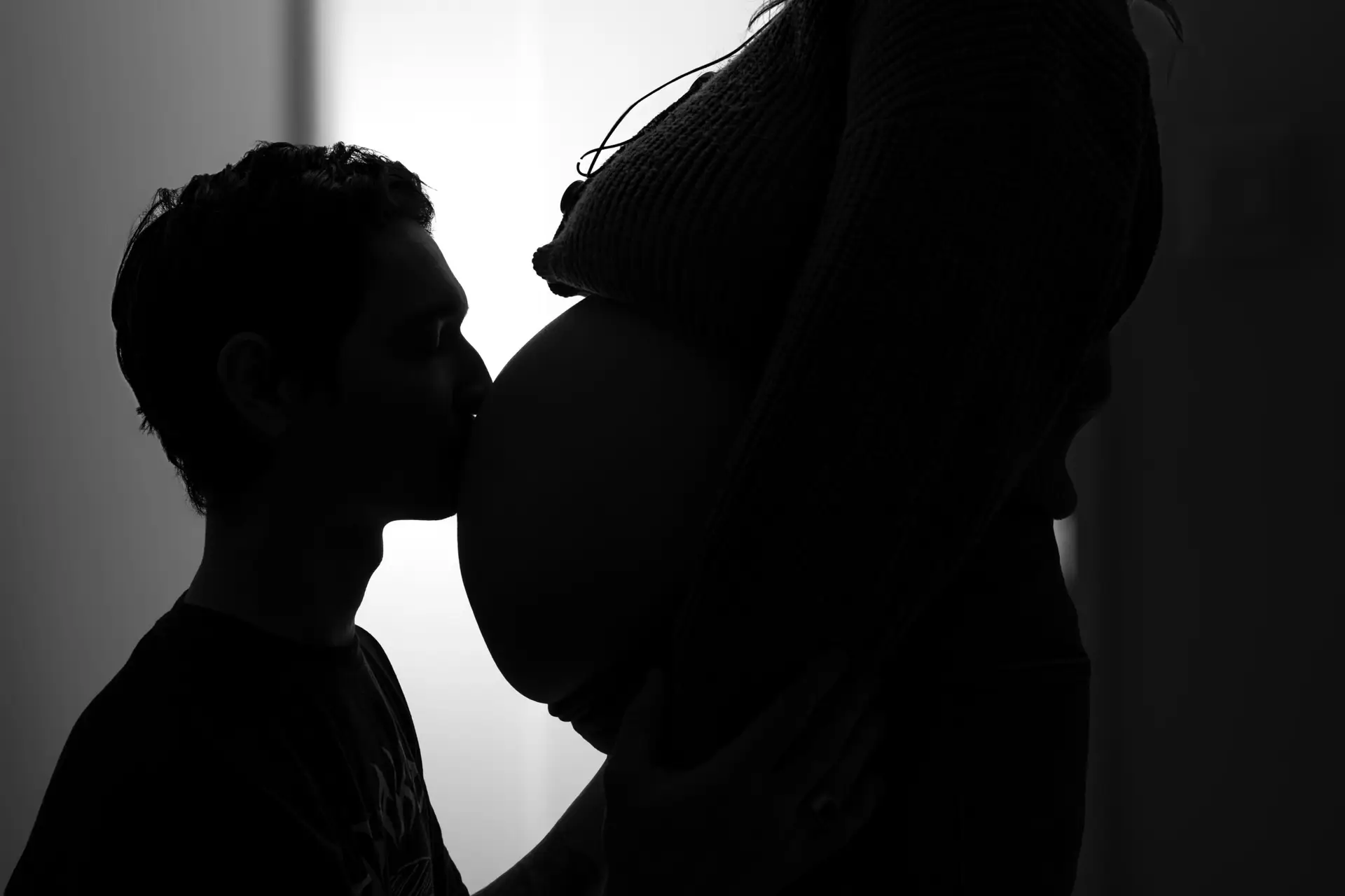 Baiser du père sur le ventre de la femme enceinte , en ombre chinoise , en noir et blanc