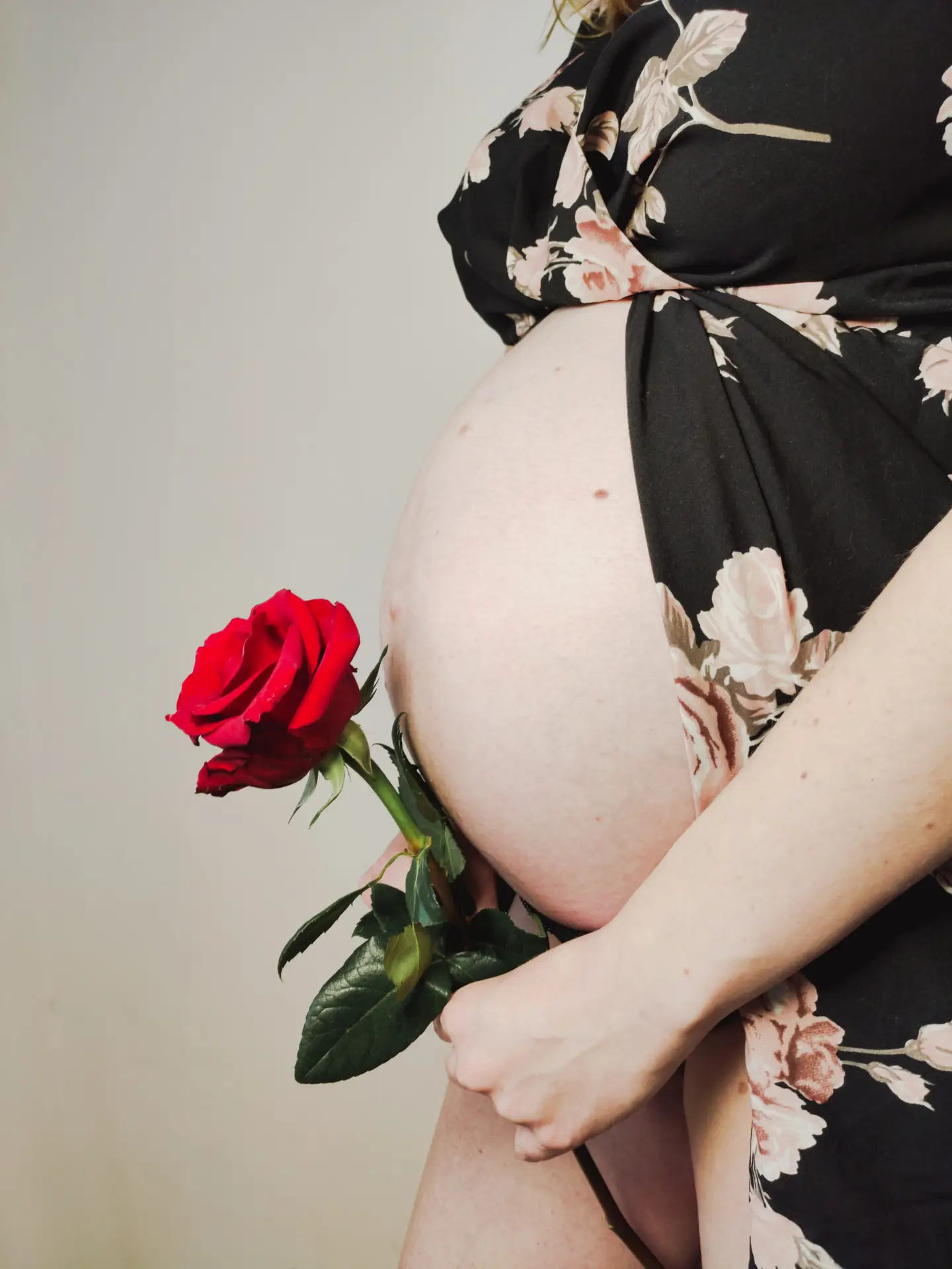 séance grossesse a la Verpillière , la femme tient une rose rouge contre son ventre