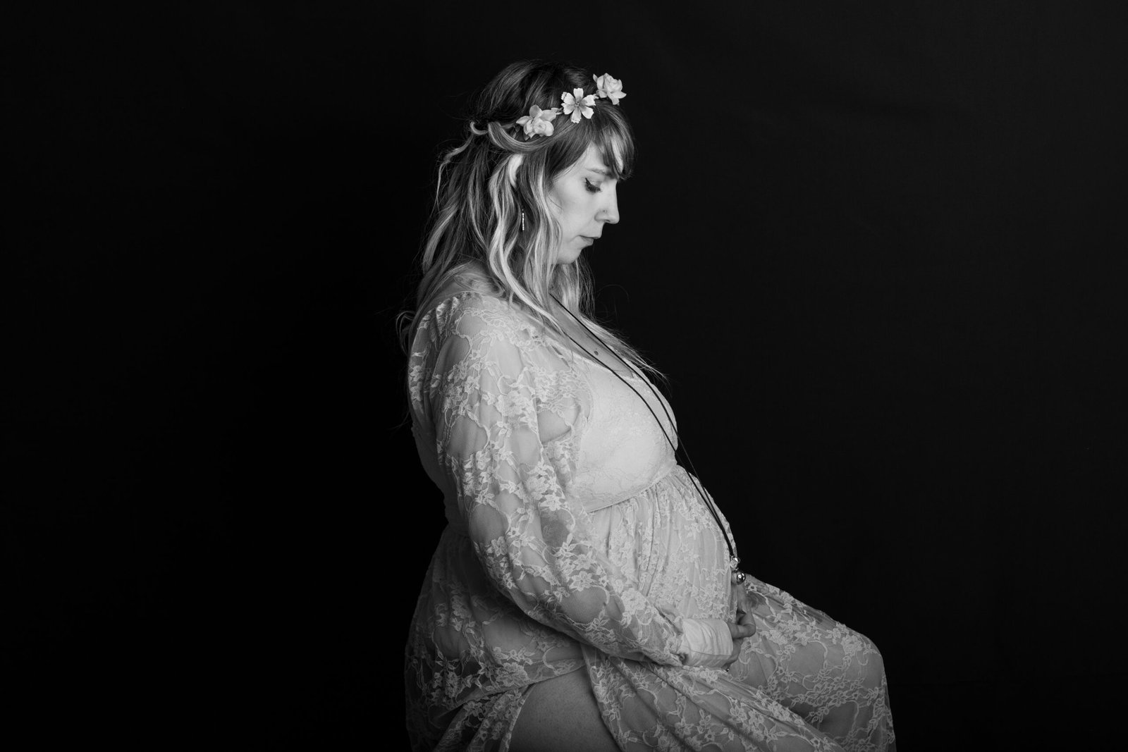 Femme enceinte pleine d'emotion a la Verpillière a genoux se tenant le ventre et détourne son regard du photographe